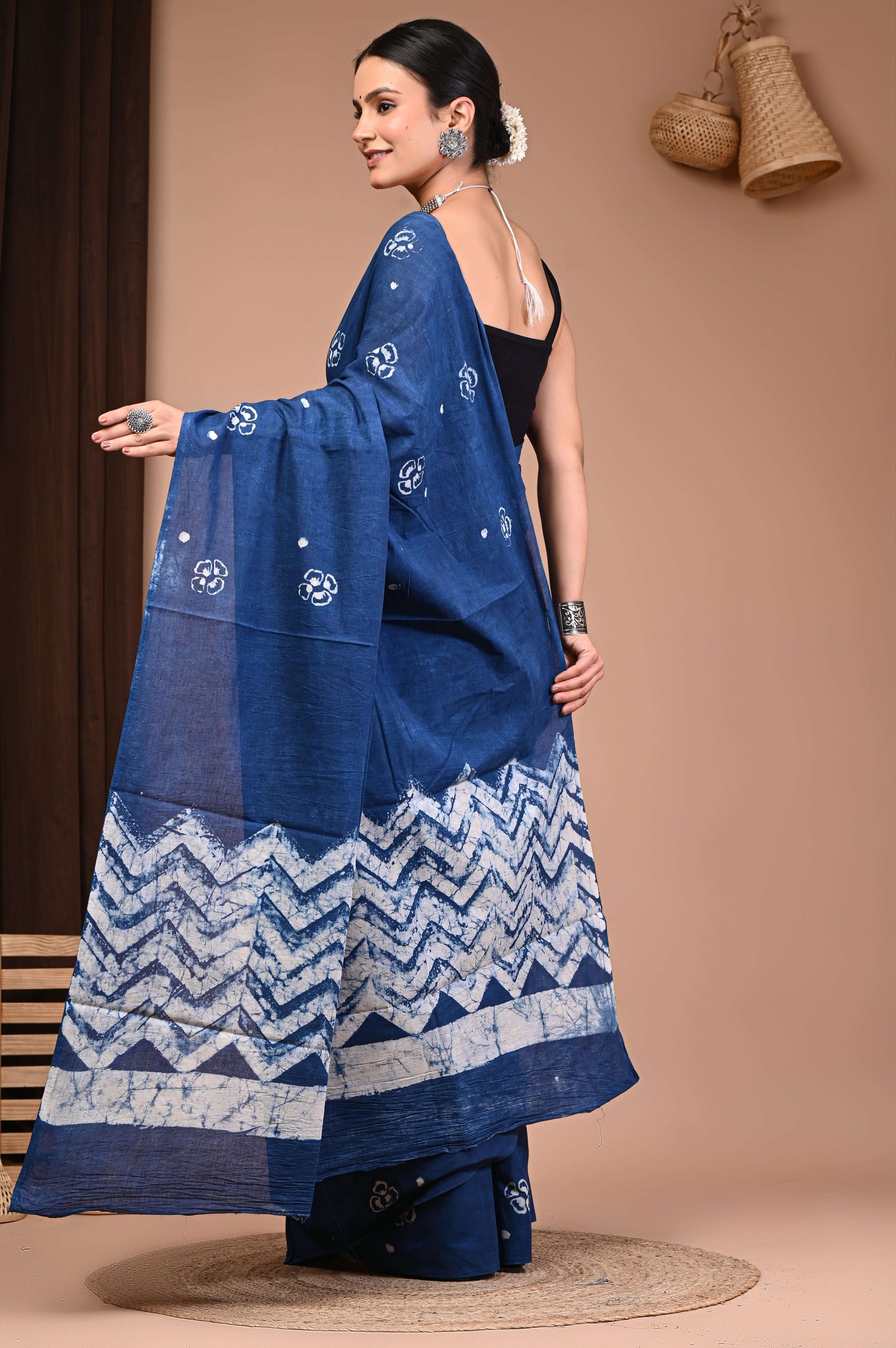 Indigo Hand Block Printed Cotton Saree in India draped by a woman, showcasing traditional floral motifs and chevron patterns.